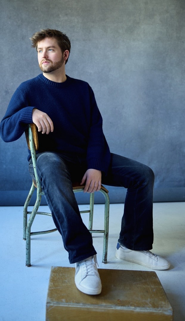 Patrick Brown seated in a studio, wearing a navy sweater