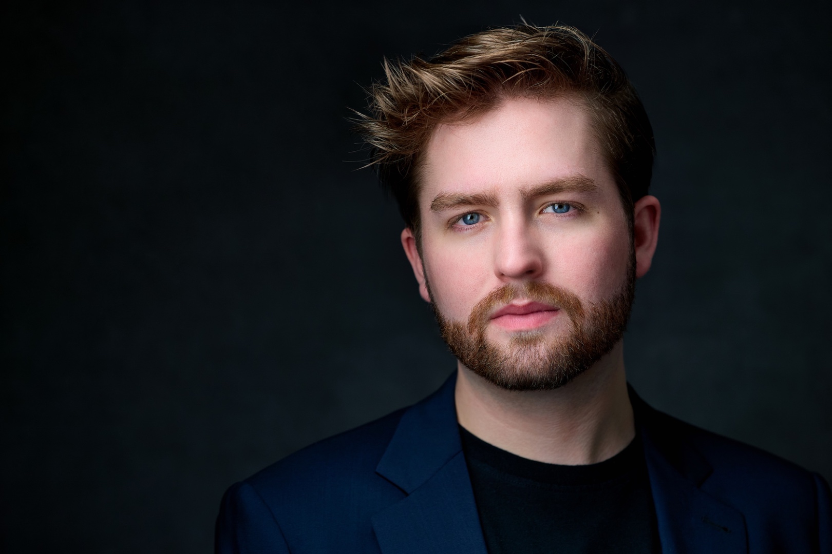 Patrick Brown headshot — dramatic, dark background, navy blazer